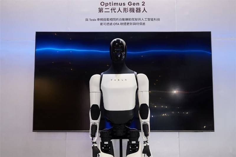 Tesla Optimus Gen 2 vor einem Messestand mit beleuchtetem Bildschirm
