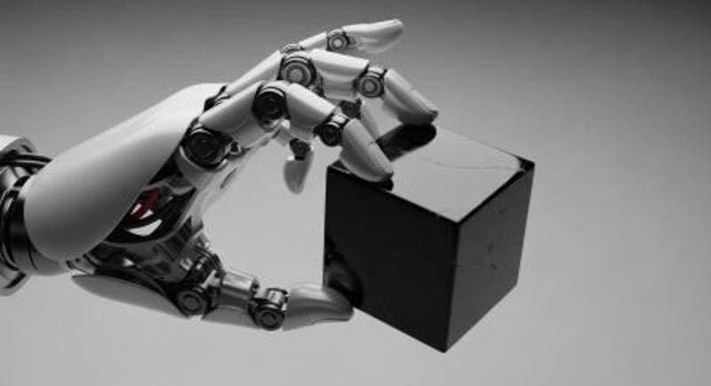 Roboterhand mit Gelenken greift einen kleinen dunklen Block