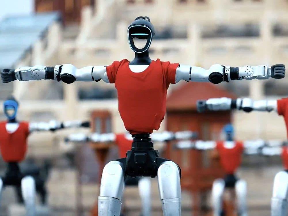 Mehrere humanoide Roboter in roten Shirts bei einer Vorführung, im Hintergrund traditionelle chinesische Architektur (Quelle: humanoid.guide)