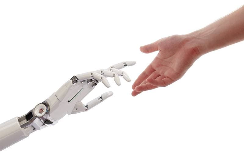 Roboterhand und menschliche Hand reichen sich auf weißem Hintergrund die Finger