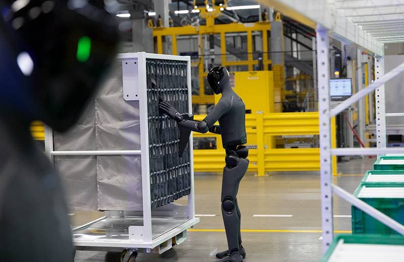 Humanoider Roboter beim Handhaben von Komponenten in einer Fabrikhalle
