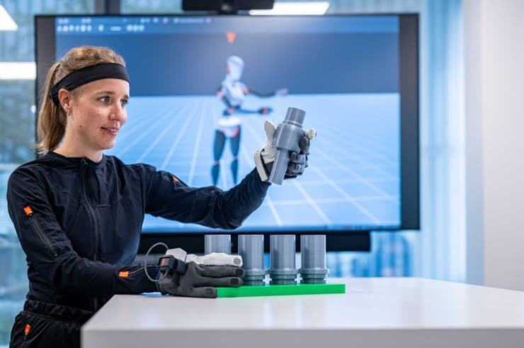 Mitarbeiterin trainiert einen Humanoiden mit Datenhandschuh und Bildschirm (Foto: BMW Group)