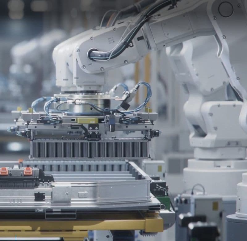 Weißer Roboterarm setzt ein Batteriemodul auf ein Montageband
