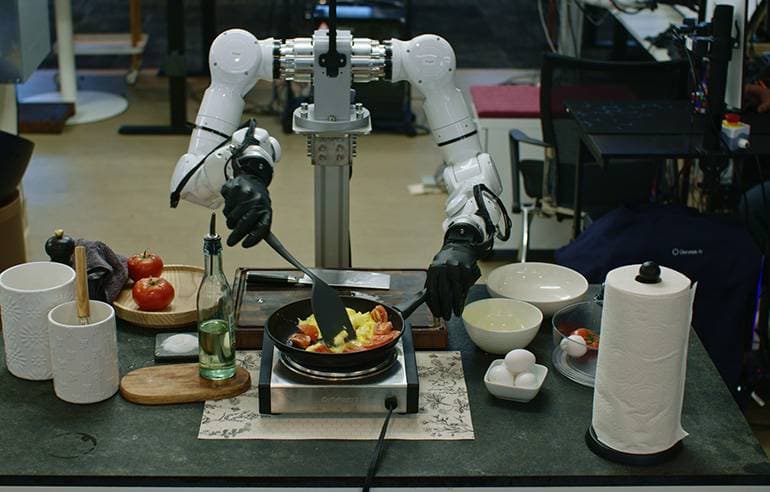 Zweiarmiger Roboter mit Greifern bei einer Küchenaufgabe (Quelle: Genesis AI)