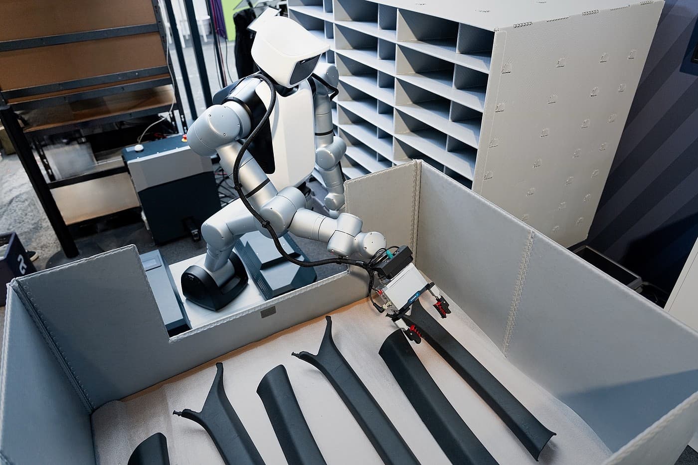 Mobiler humanoider Roboter von Agile Robots greift ein schwarzes Bauteil aus einem Behälter in einer Testumgebung