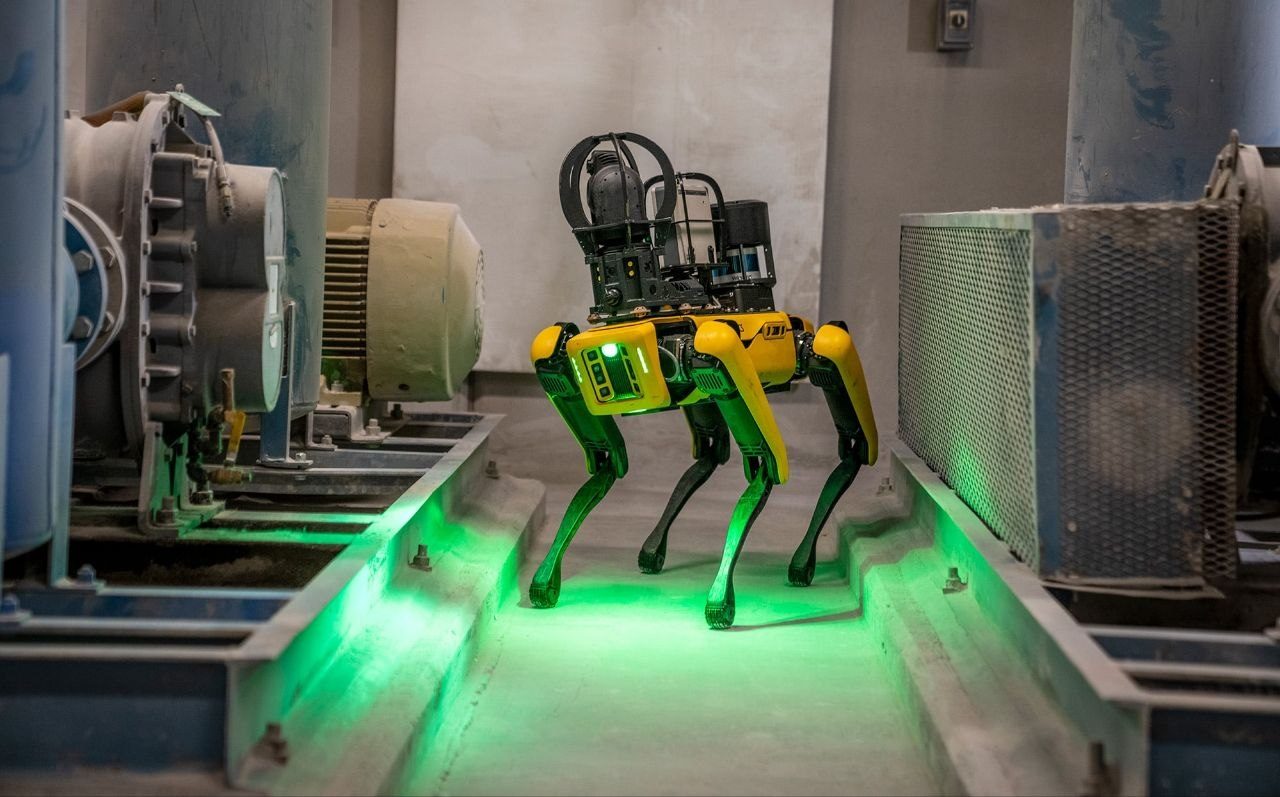 Gelb-schwarzer Spot-Roboter mit Sensoraufbau zwischen Industriemaschinen